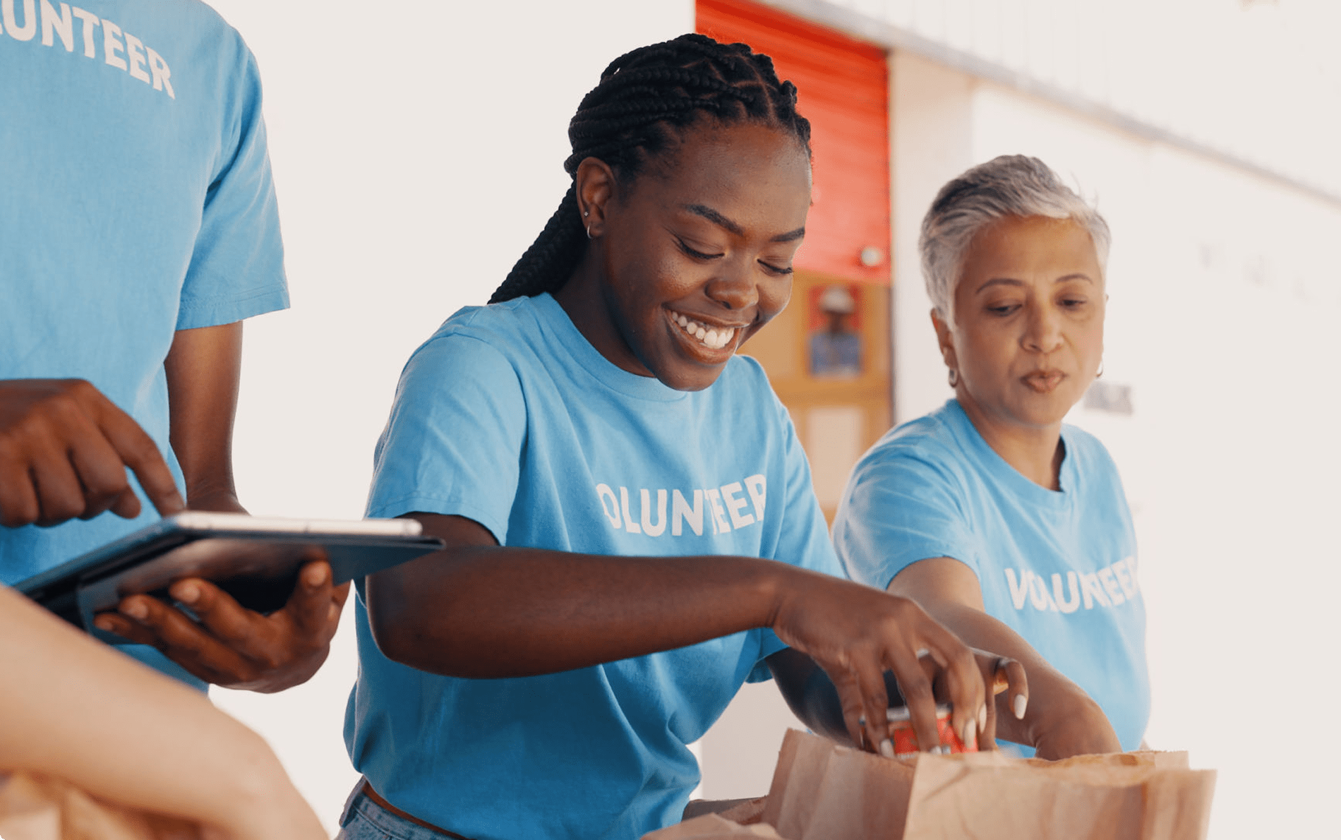 Volunteers packing food into paper bags.